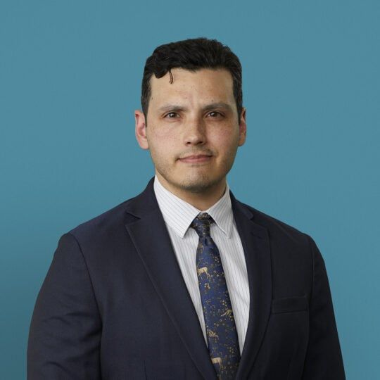 Professional headshot of Damian Valencia, MD in dark suit and patterned tie