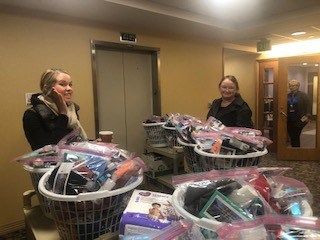 Two women organizing donated items in baskets for healthcare charity drive
