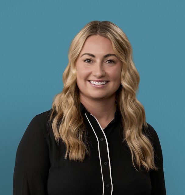 Professional headshot of Katlyn Robison, APRN-CNP, smiling in black blouse against blue background