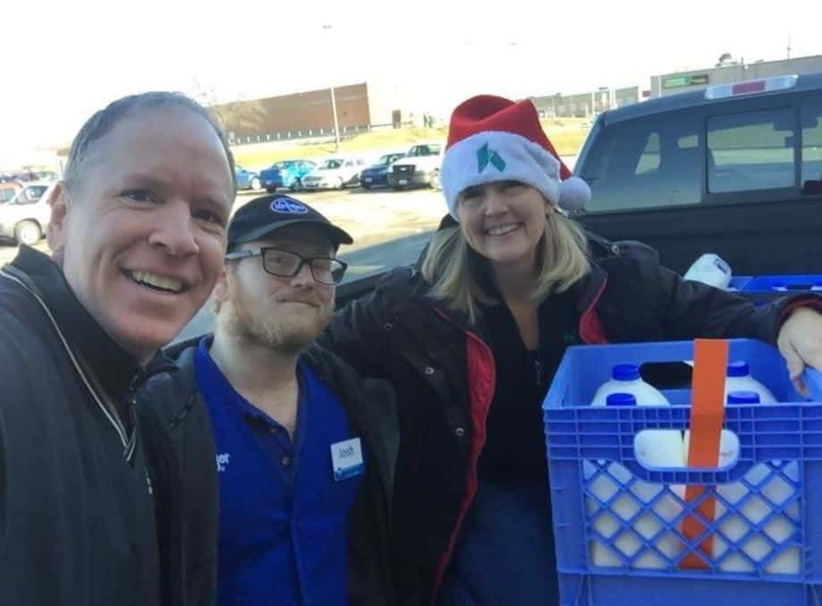 Three healthcare volunteers posing together with blue donation crates during community outreach event