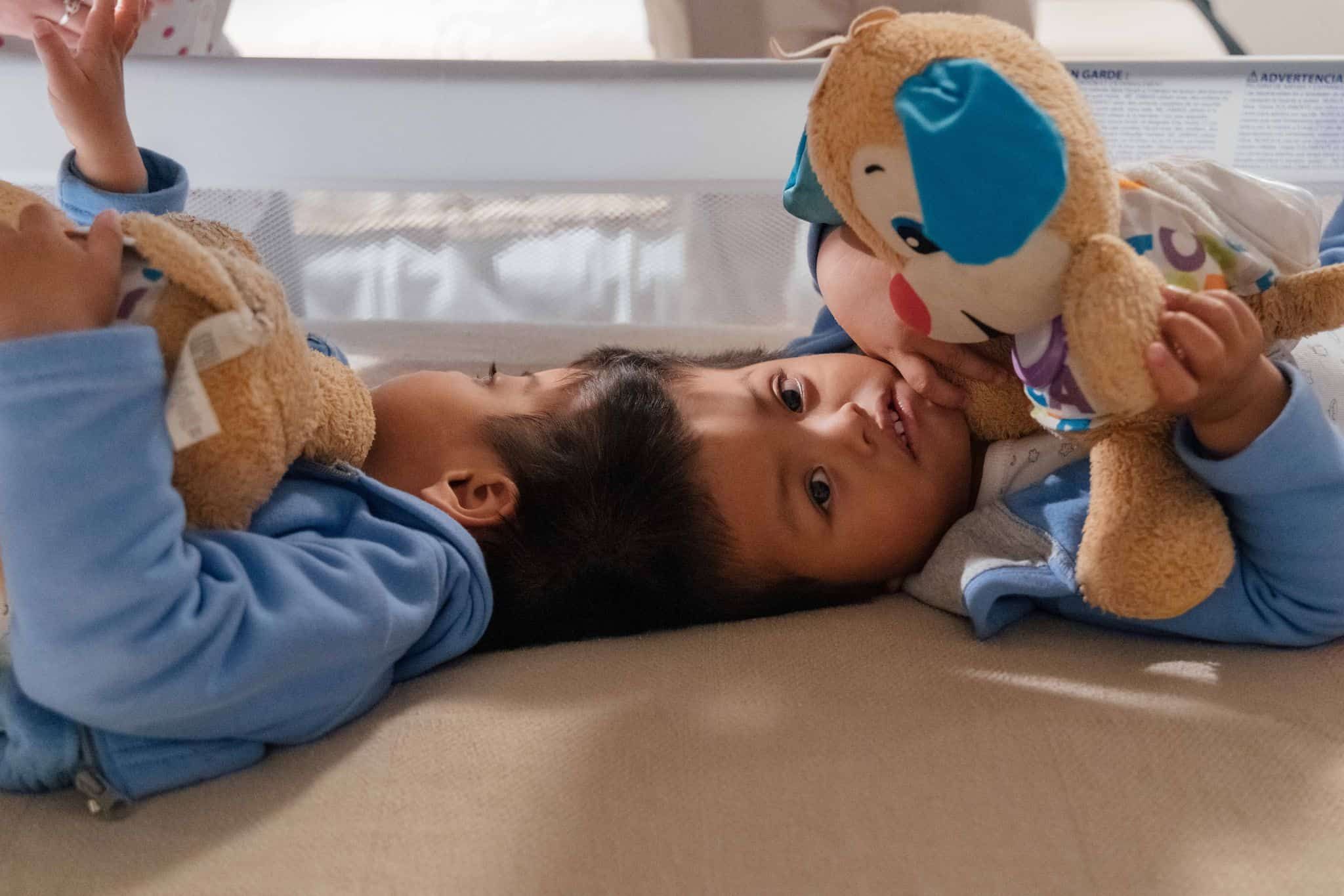 Child patient lying in hospital bed holding colorful stuffed animal toy
