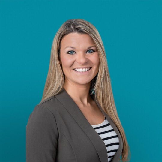 Professional headshot of Laura Striebel-Williams, DO smiling in gray blazer against teal background