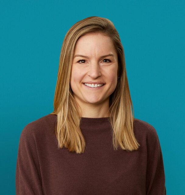 Professional headshot of Mary Mullen, MD smiling in brown sweater against teal background
