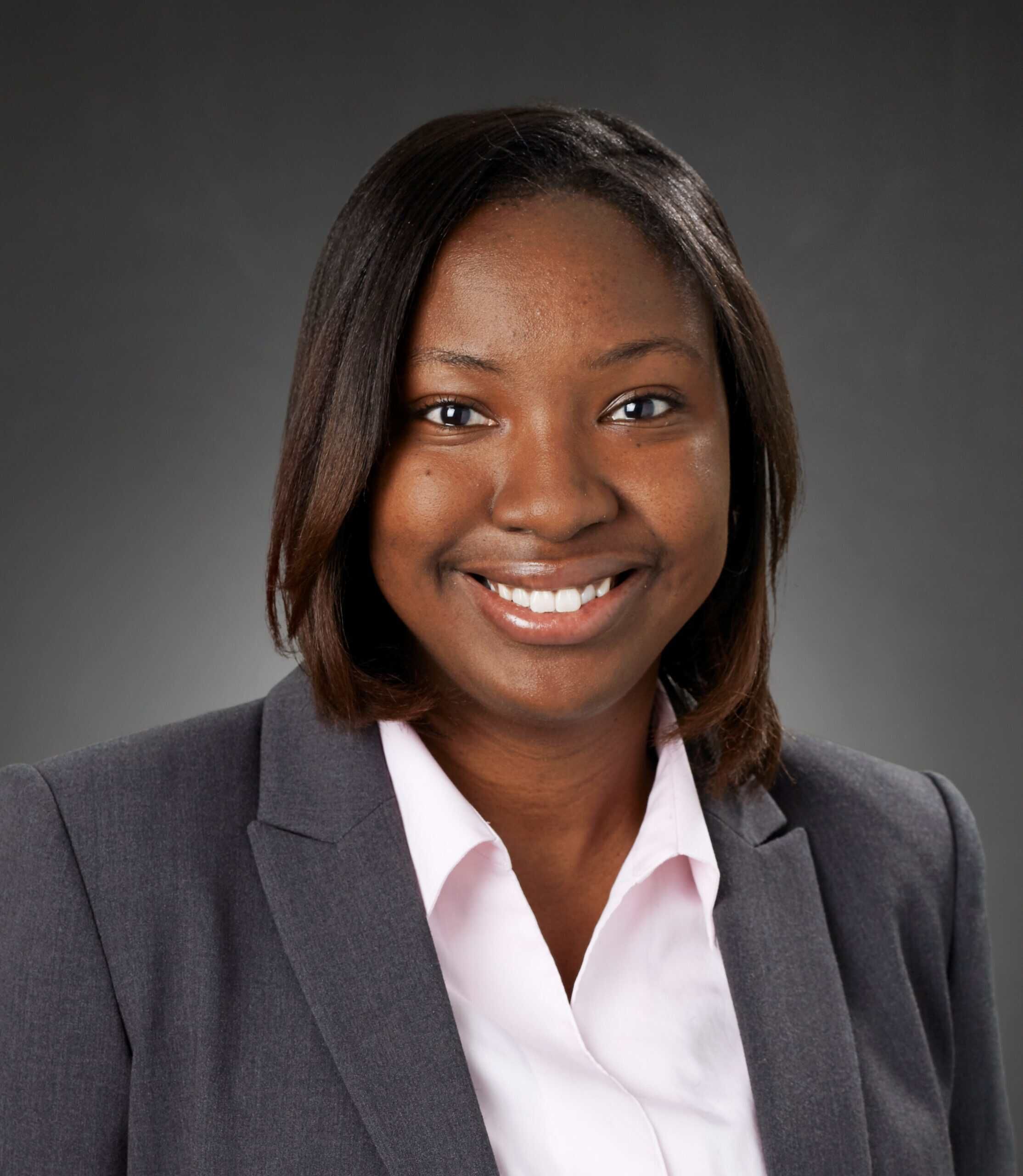 Professional headshot of Vimbai Mazani wearing gray blazer and white shirt, smiling