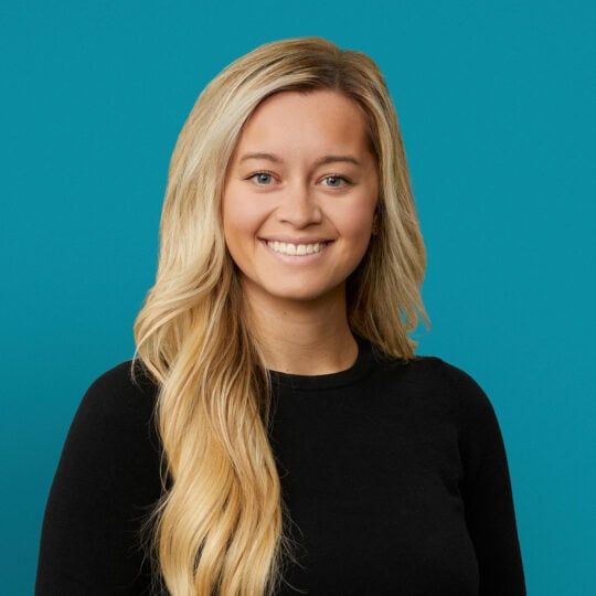 Professional headshot of Megan Davis-Reed, APRN-CNP smiling in black top against teal background