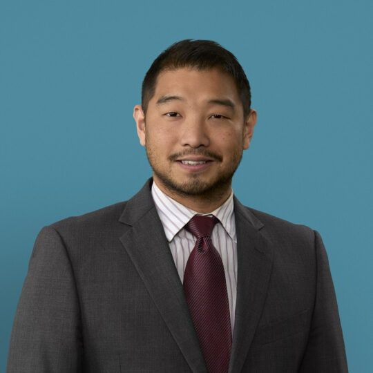 Professional headshot of Moses Chung, PA-C in gray suit with burgundy tie