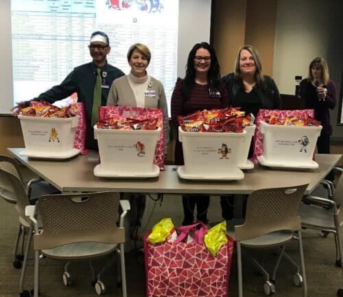 Healthcare staff members standing behind table with donation baskets filled with candy and gifts