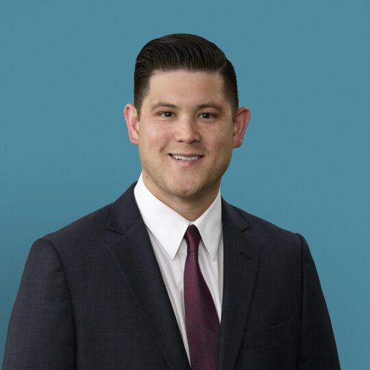 Professional headshot of Dr. Nate Han in dark suit and burgundy tie