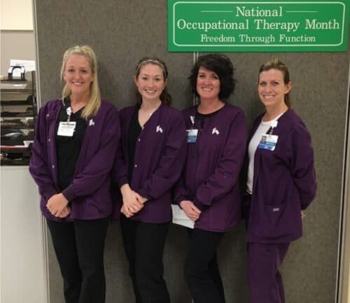 Four occupational therapists in purple uniforms celebrating National Occupational Therapy Month