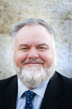 Professional headshot of Dr. O'Neal, smiling man with gray beard in suit and tie