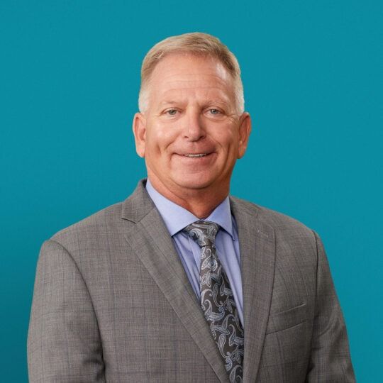 Professional headshot of Patrick J. Lytle, DO in gray suit against teal background
