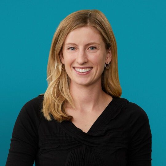 Professional headshot of Rachel Booth, DO smiling in black top against teal background