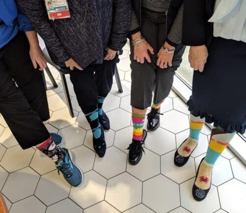Healthcare workers displaying colorful patterned socks in office setting