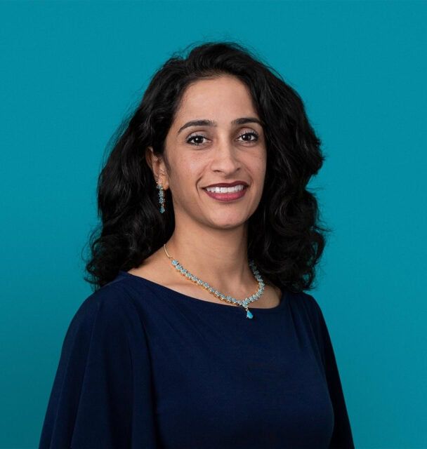 Professional headshot of Dr. Sunila Paul wearing navy blue top against teal background