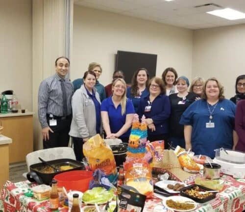 Healthcare staff gathered around table with taco ingredients for Taco Tuesday event
