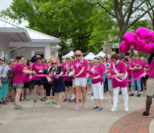 Women in pink shirts cutting ribbon at Walk for Women's Wellness event