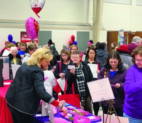 Woman distributing red gift bags to attendees at Kettering Health community event