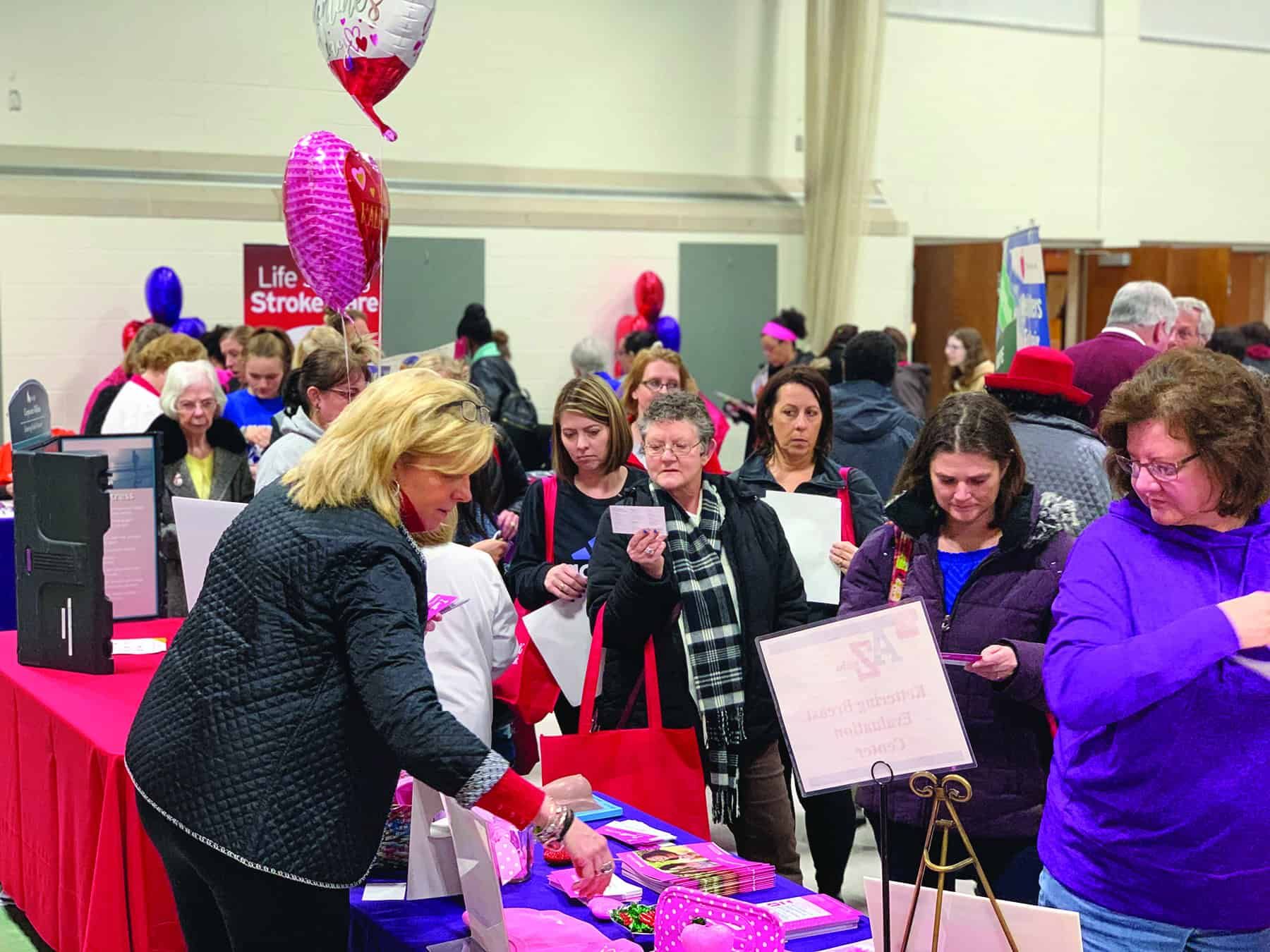 Woman distributing red gift bags to attendees at Kettering Health community event