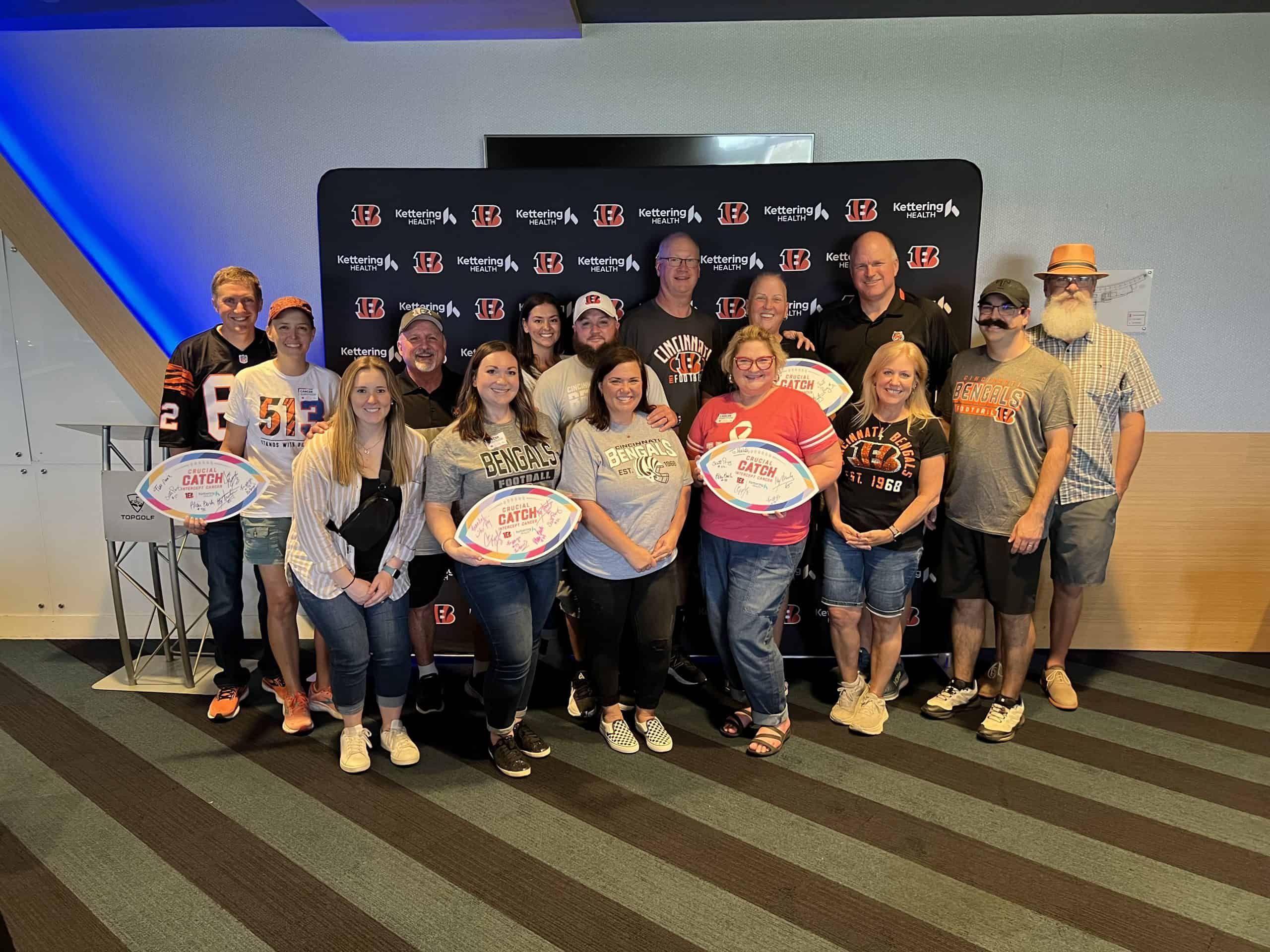Group of Bengals fans posing with football-shaped awards at Kettering Health event