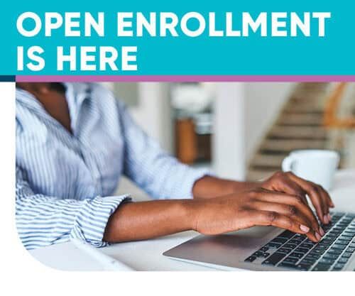 Person typing on laptop with "Open Enrollment is Here" text overlay