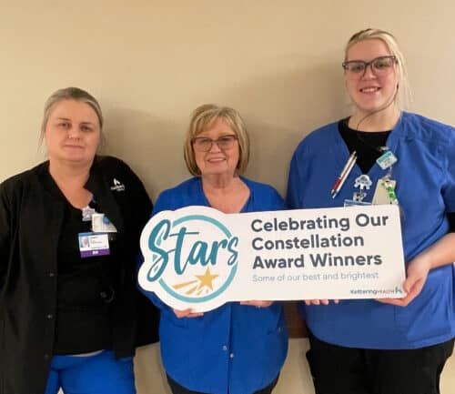 Three healthcare workers holding Constellation Award Winners banner celebrating staff recognition