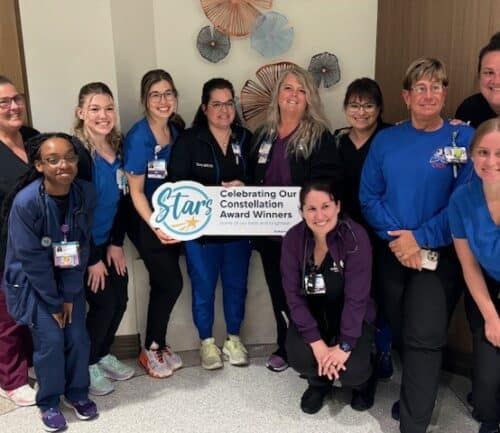 Healthcare team celebrating with Constellation Award Winners banner in hospital setting