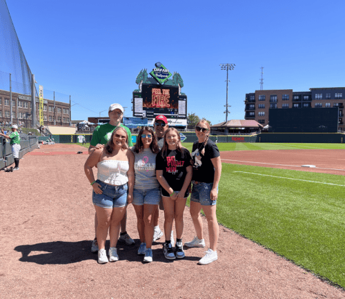 Five people posing together at Dayton Dragons baseball stadium during cancer awareness event