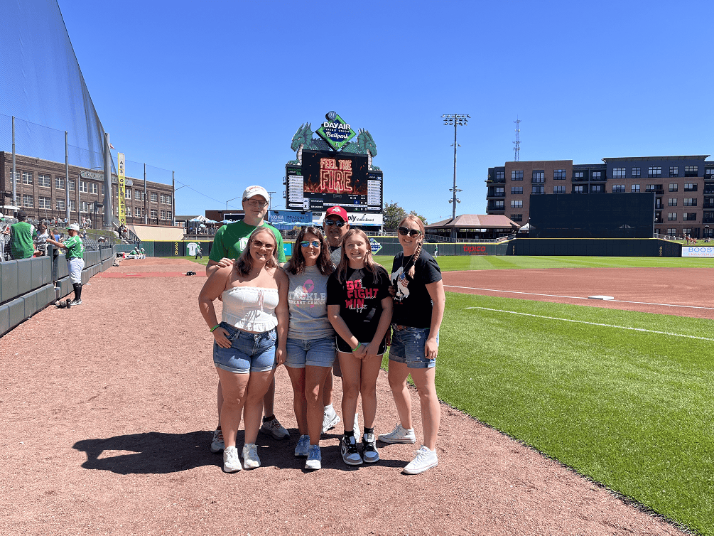 Five people posing together at Dayton Dragons baseball stadium during cancer awareness event