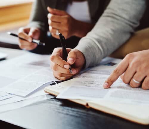People reviewing medical documents and paperwork with pens at desk