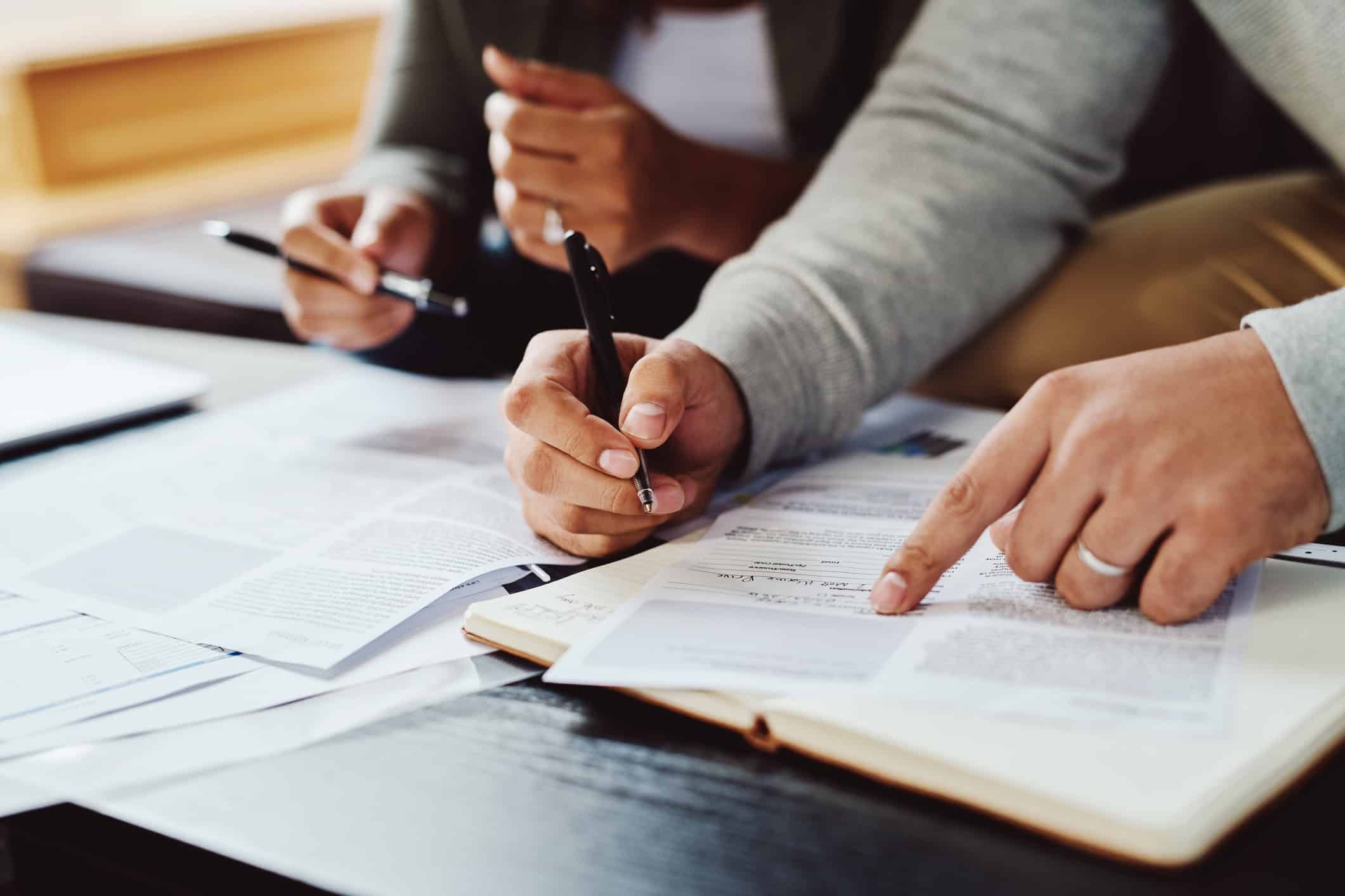 People reviewing medical documents and paperwork with pens at desk