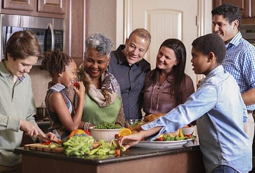 Multigenerational family gathering around kitchen island preparing Thanksgiving meal together