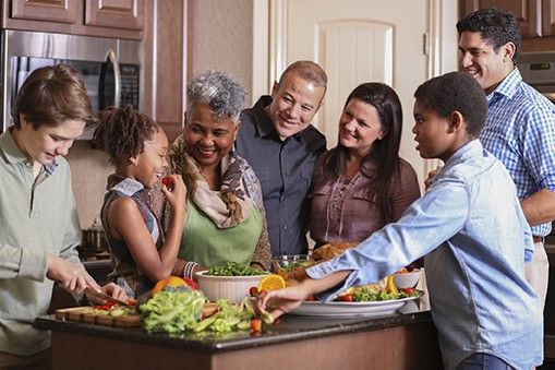 Multigenerational family gathering around kitchen island preparing Thanksgiving meal together