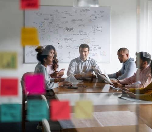 Business team collaborating around conference table with strategy whiteboard in background