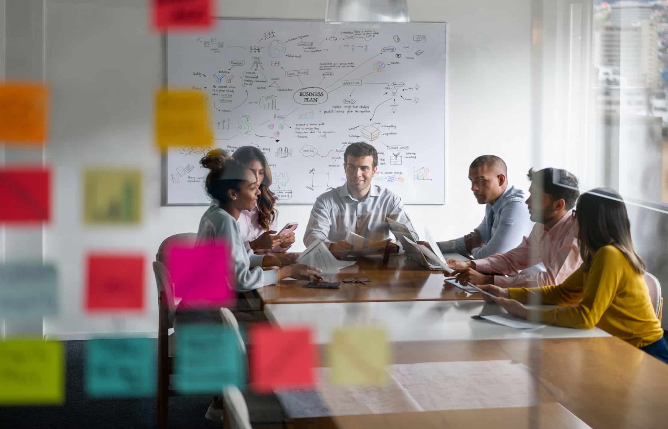 Business team collaborating around conference table with strategy whiteboard in background