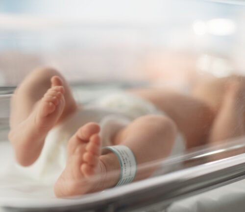 Newborn baby lying in hospital bassinet with identification bracelet on ankle