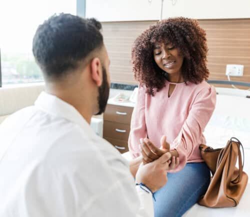 Doctor examining woman's injured wrist in bright medical office setting