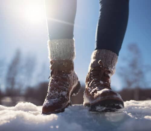 Person walking in winter boots through snow on sunny day
