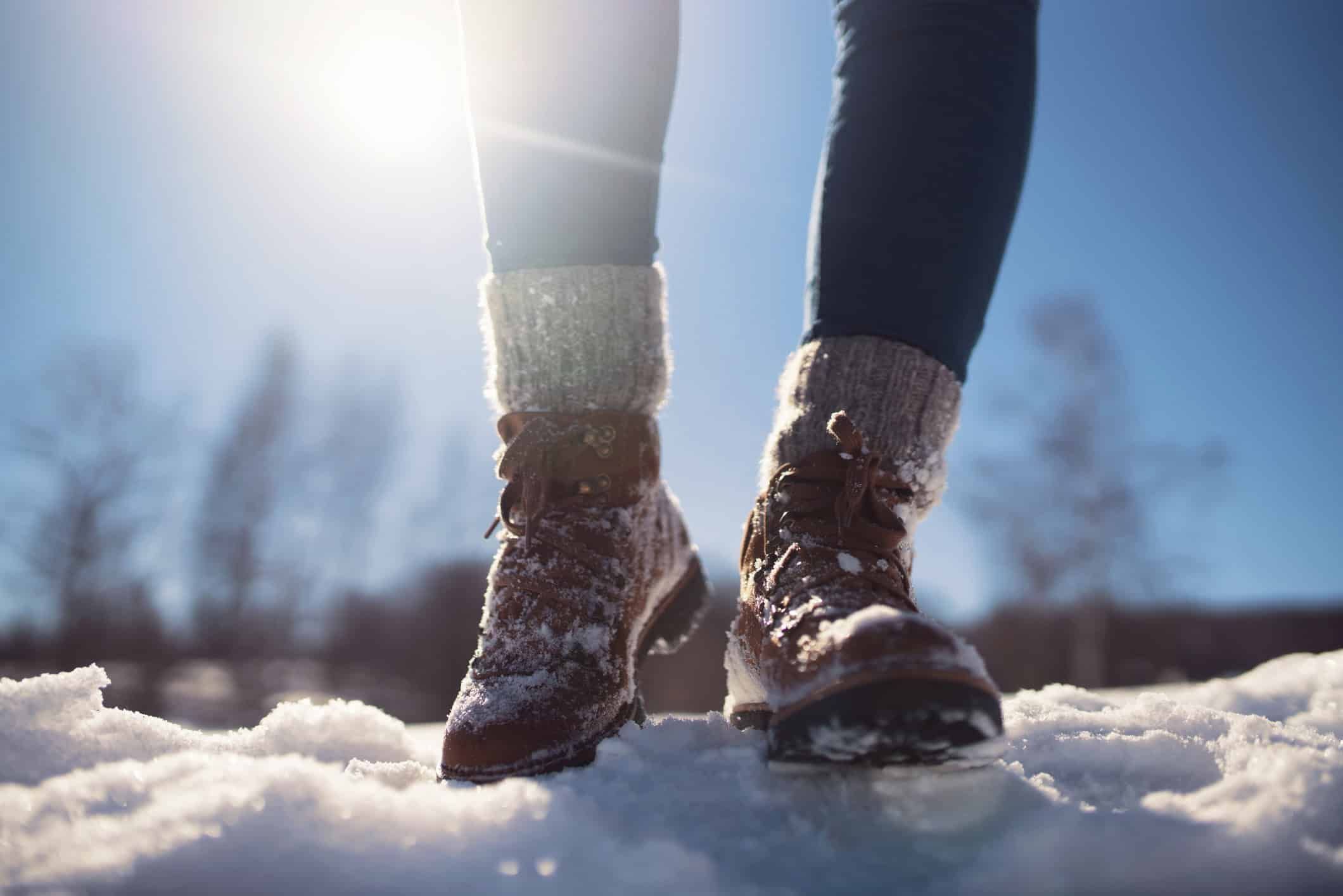 Person walking in winter boots through snow on sunny day