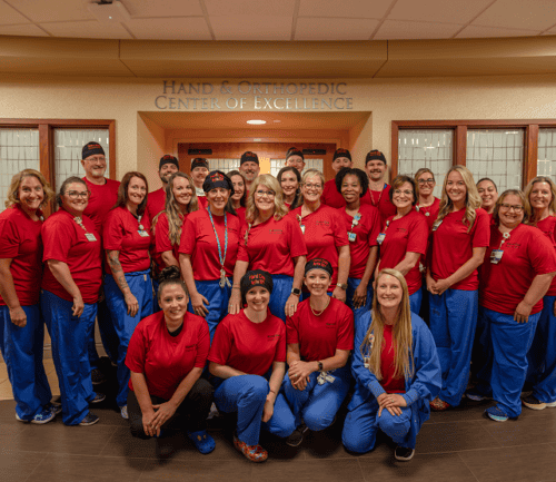 Healthcare team in matching red scrubs posing together at Hand & Orthopedic Center