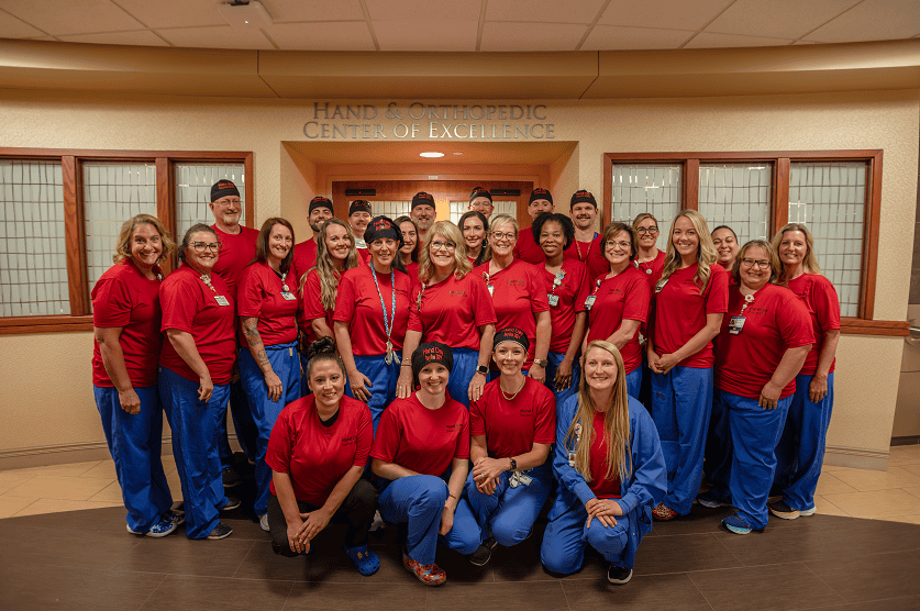 Healthcare team in matching red scrubs posing together at Hand & Orthopedic Center