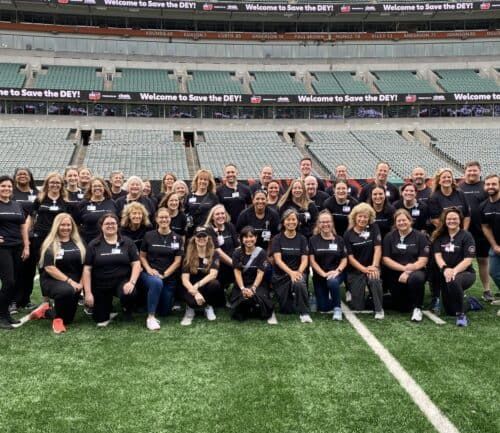 Large group of Kettering Health employees in matching black shirts posing on football field