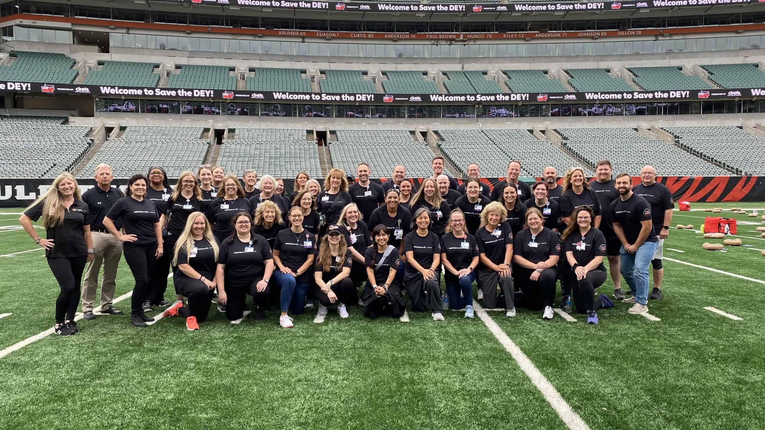 Large group of Kettering Health employees in matching black shirts posing on football field