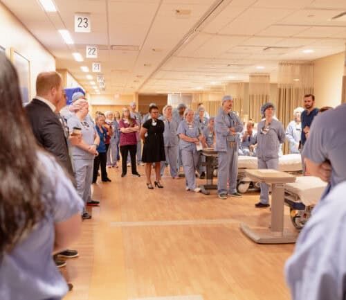 Healthcare staff gathering in hospital unit during facility tour or meeting
