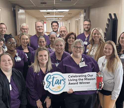 Healthcare team celebrating with "Star Award Winner" banner in hospital hallway