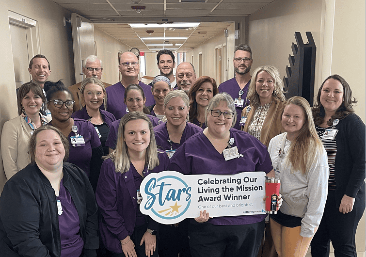 Healthcare team celebrating with "Star Award Winner" banner in hospital hallway