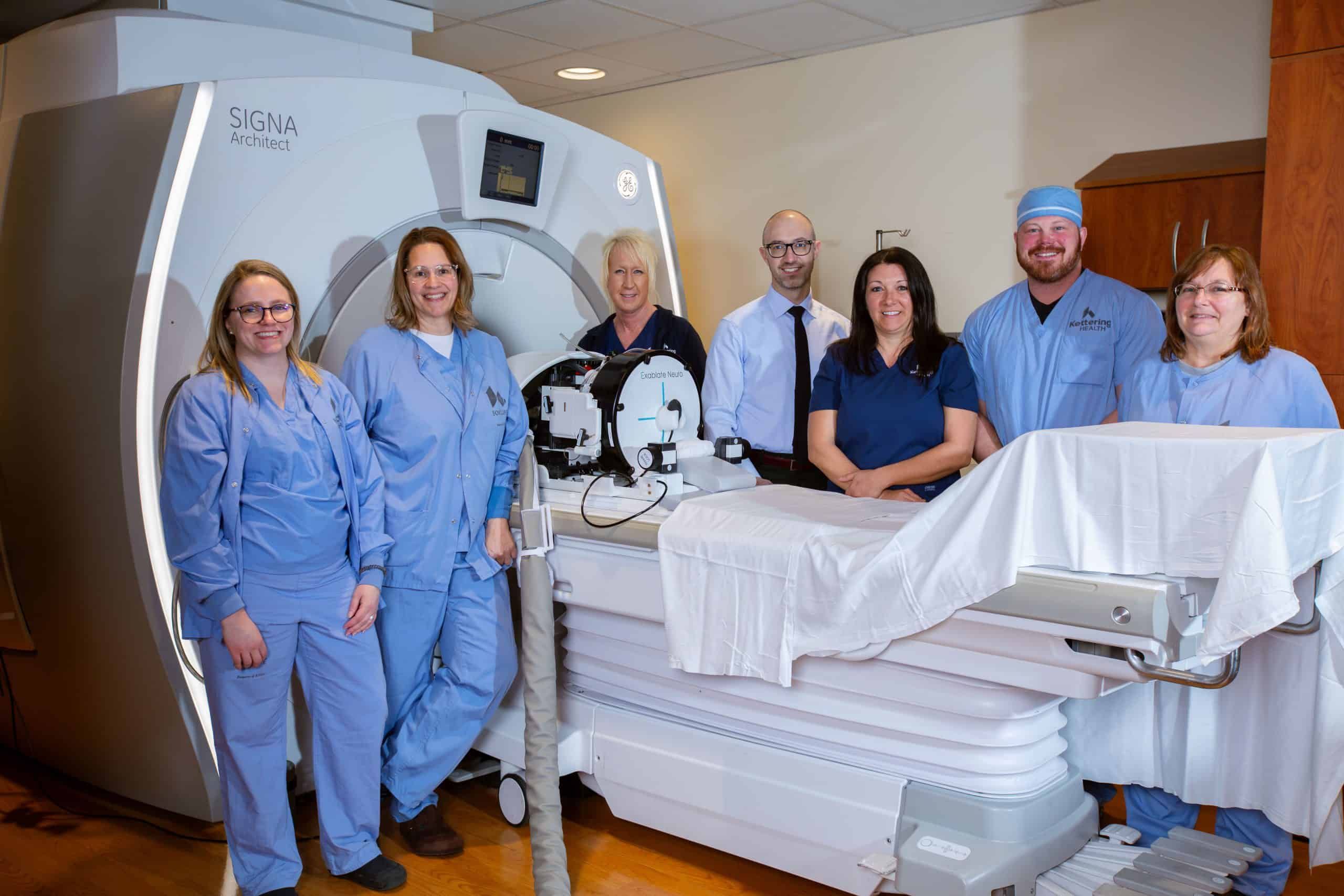 Medical team posing with SIGNA Architect MRI machine and hospital bed equipment