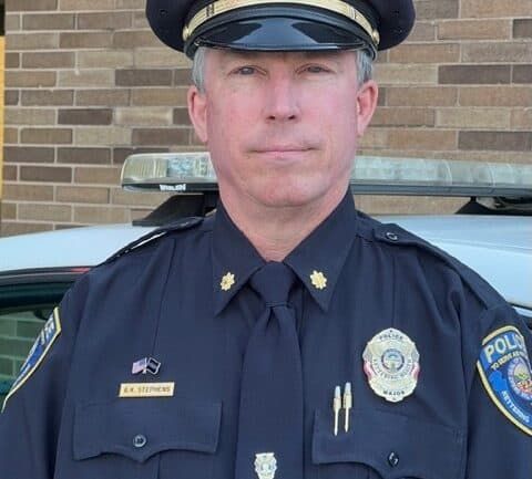 Police officer in uniform standing in front of patrol car