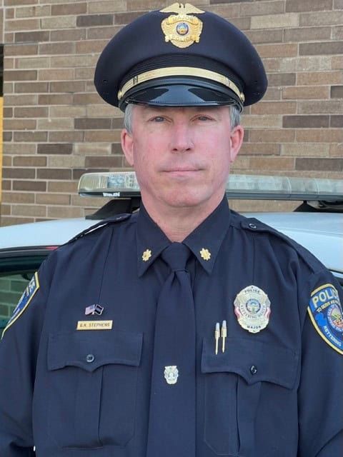 Police officer in uniform standing in front of patrol car