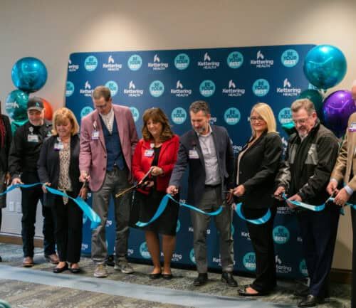 Group of people cutting blue ribbon at Kettering Health facility opening ceremony