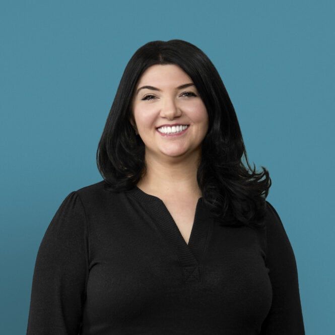 Professional headshot of Scarlett Sarbaugh smiling in black top against teal background